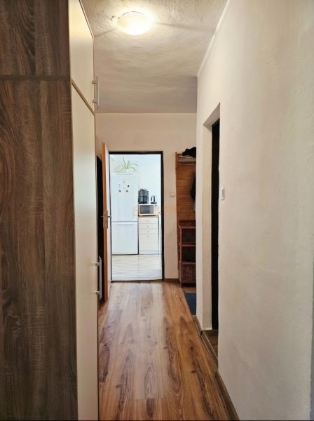Egy családi ház folyosója fa dekorációjú padlóval és kilátással a konyhára.