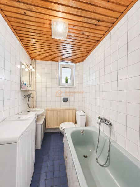 Fürdőszoba csempékkel, kék padlóval, káddal és fa mennyezettel egy családi házban.
