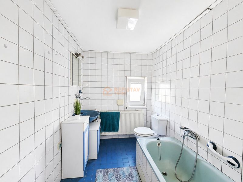 Fürdőszoba zuhanyzóval és káddal, fehér csempével burkolva egy családi házban.