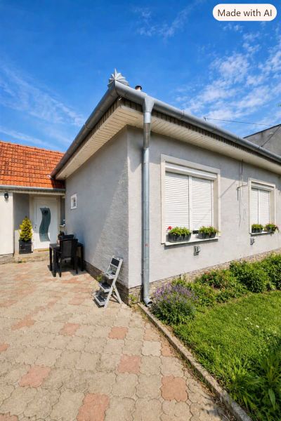Családi ház Szelicén, virágokkal az ablakoknál és kövezett udvarral.