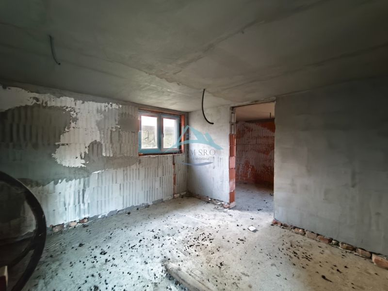 Családi ház belső tere befejezetlen vakolattal és betonpadlóval.