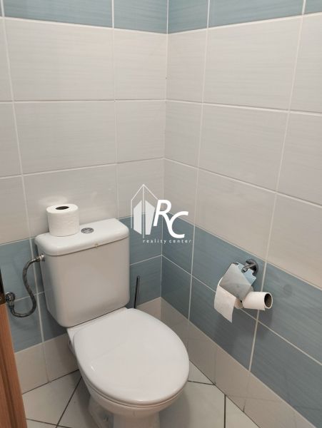 Világos csempékkel és WC-vel ellátott fürdőszoba egy kétszobás lakásban.