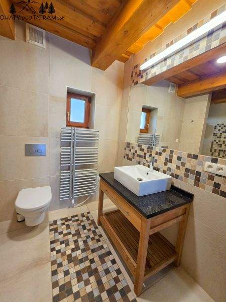 Fürdőszoba a házikóban zuhanyzóval, mosdóval, WC-vel és mozaik csempékkel.