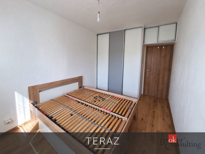 Hálószoba fa dekorációjú padlóval és beépített szekrénnyel egy háromszobás lakásban.