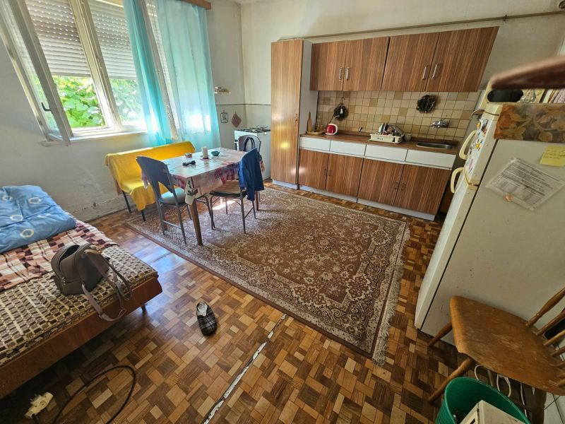 Konyha családi házban étkezőasztallal, konyhabútorral és fa dekorációjú padlóval.
