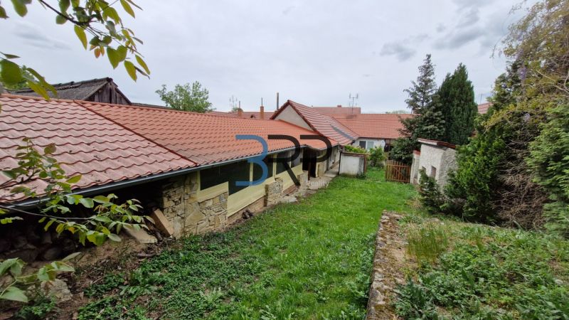 Kert a családi ház mellett Mokrý Hájban, kőfallal és piros tetőfedéssel.
