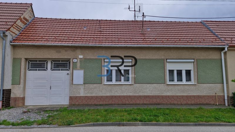 Családi ház Mokrý Hájban piros tetővel és garázsajtókkal.
