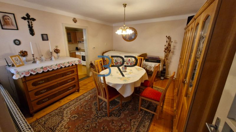 Ebédlő egy családi házban fa dekorációval, asztallal és komóddal.