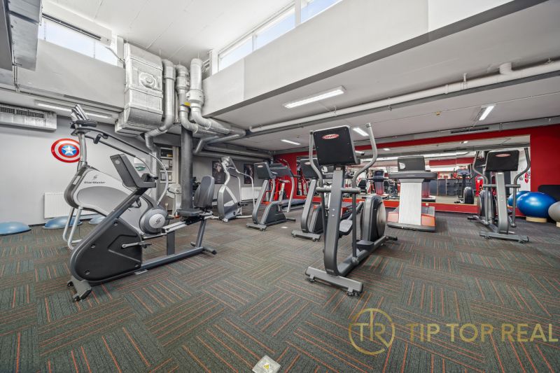 Fitnesz központ edzőfelszereléssel, tükrökkel és légtechnikával kereskedelmi helyiségekben.