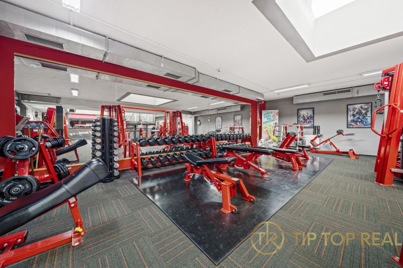 Fitneszközpont edzőgépekkel, padokkal és tükrökkel a kereskedelmi helyiségekben.