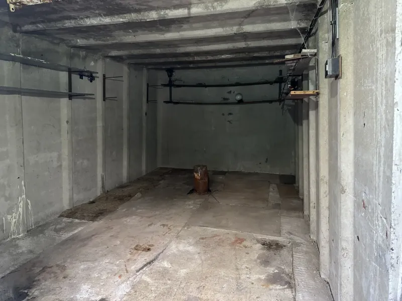 Betongarázs Pozsony-Újvárosban, egyszerű falakkal és tárolópolcokkal.