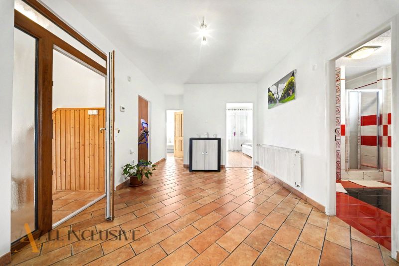 Tágas folyosó csempézett padlóval egy családi házban, fa belső elemekkel.