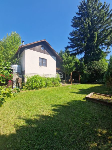 Egy zsolnai nyaraló kertje gyepes területtel és háttérben magas fákkal.