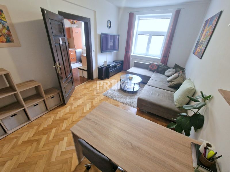 A háromszobás lakás nappalija kényelmes ülőgarnitúrával és fa mintázatú padlóval rendelkezik.