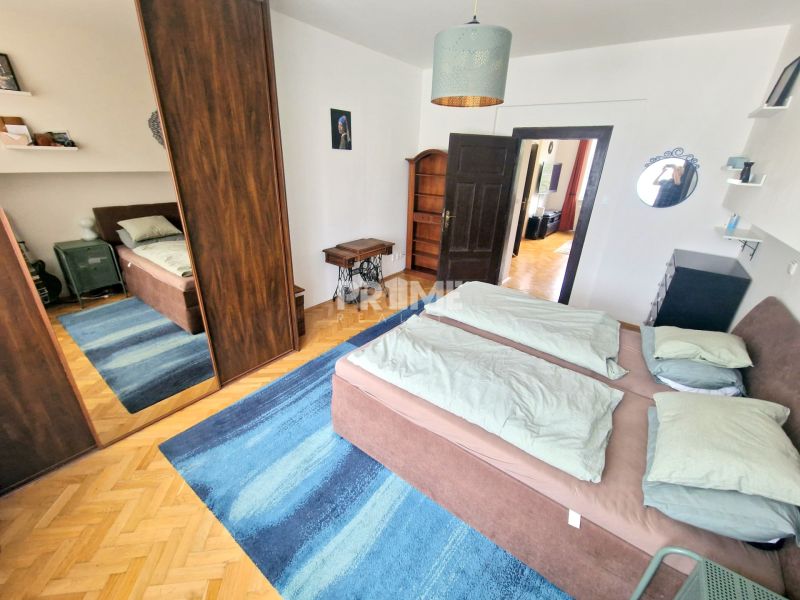 Hálószoba egy háromszobás lakásban ággyal, tükrös szekrénnyel és kék szőnyeggel.