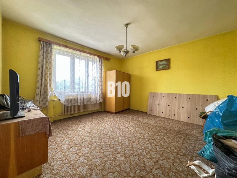 Szoba egy családi házban szőnyeggel, bútorokkal és függönyökkel az ablakon.