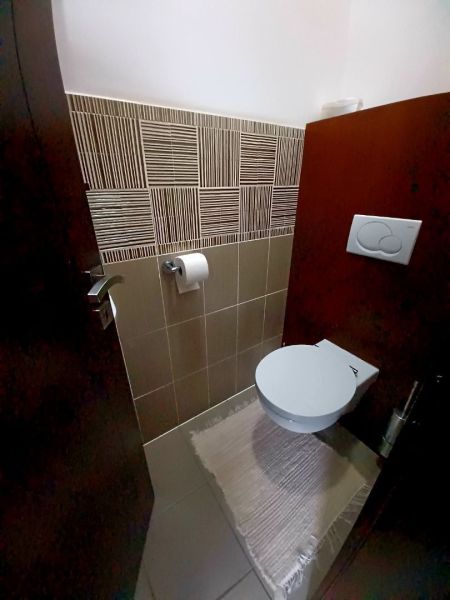 Fürdőszoba családi házban kerámia burkolattal és függesztett WC-vel.