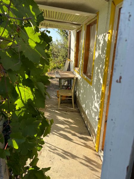 A Bankán található házikó verandája szőlőlombbal körülvett faasztallal.