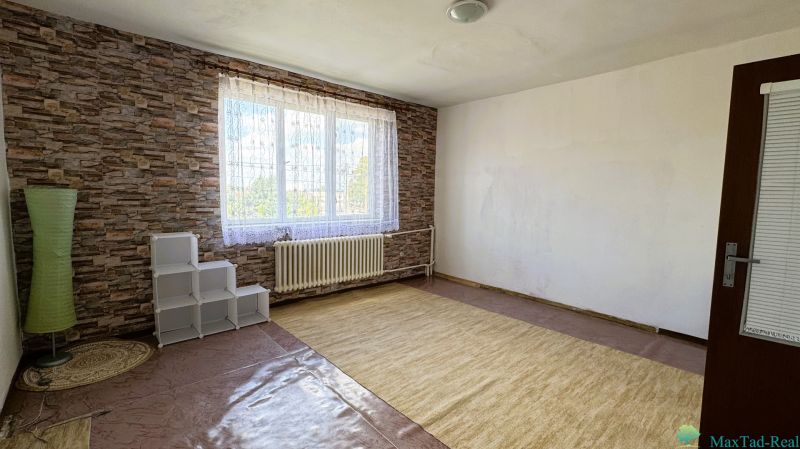 Szoba nagy ablakkal, szőnyeggel és téglamintás falakkal egy családi házban.