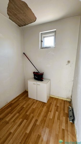 Kis szoba ablakkal, szekrénnyel és fa mintázatú padlóval egy családi házban.