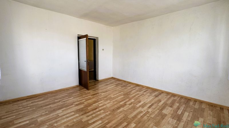 Szoba családi házban fa dekorációjú padlóval és nyitott ajtókkal.