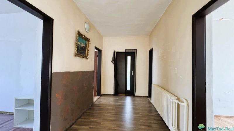 Egy családi ház folyosója fa dekorációs padlóval és egy képpel a falon.