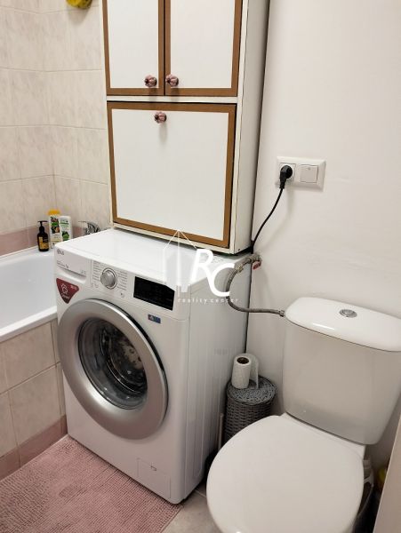 Egy szobás lakás fürdőszobája mosógéppel, káddal és WC-vel.