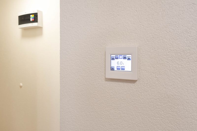 Állítható termosztát a garzonlakás falán, egyszerű dizájn, fehér háttér.