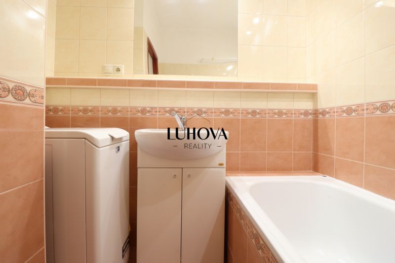 Fürdőszoba egy kétszobás lakásban káddal és mosógéppel, színes csempékkel burkolva.