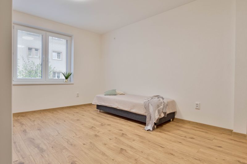 Garzonlakás ággyal, fa dekor padlóval és ablakkal, kilátással.
