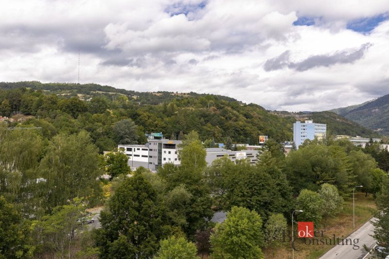 Kilátás a zöldövezetre és épületekre Besztercebányán, az Északi utcán, dombokkal körülvéve.