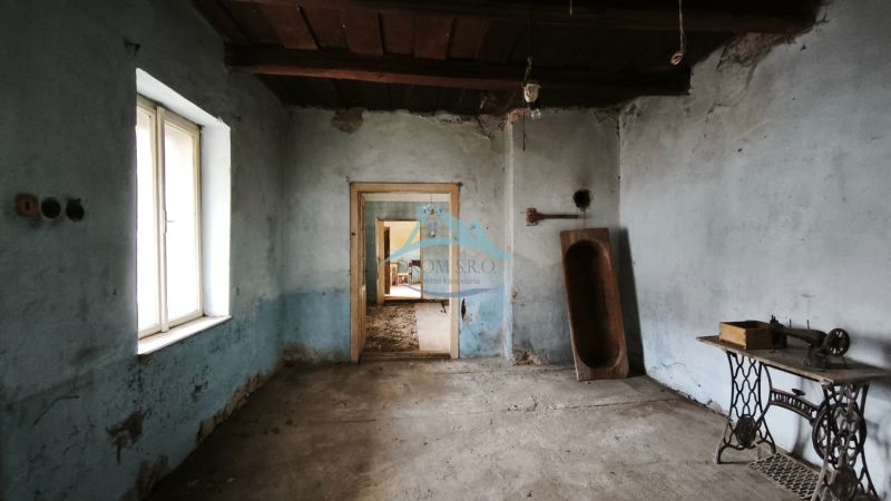 Egy szoba családi házban kék falakkal, régi varrógéppel és fa teknővel.