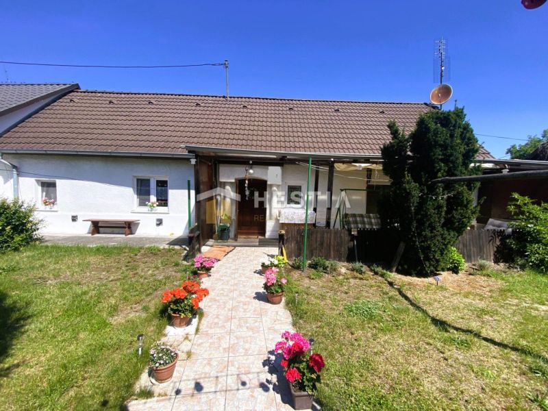 Családi ház Borsky Mikulášban kerttel és virágokkal a verandán lévő cserepekben.