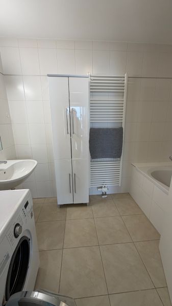 Fürdőszoba egy háromszobás lakásban, fehér bútorokkal és mosógéppel.