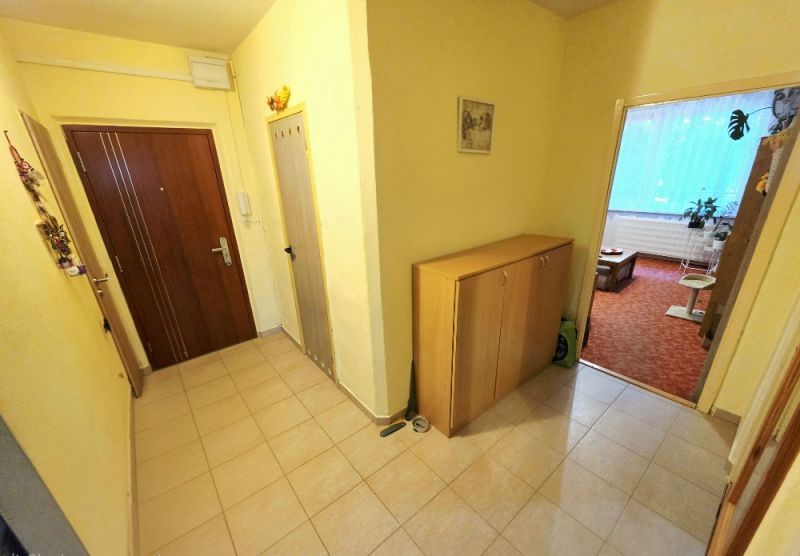 Előszoba egy 4 szobás lakásban bejárati ajtóval és tárolóbútorral.