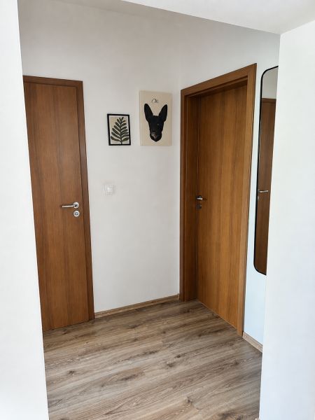 Folyosó egy 3 szobás lakásban, fa dekorációjú padlóval és fa ajtókkal.