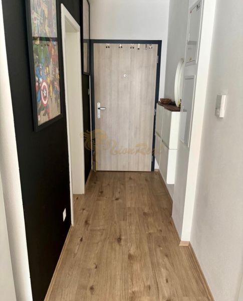 Folyosó egy kétszobás lakásban, fa dekor padlóval és fa dekor ajtókkal.