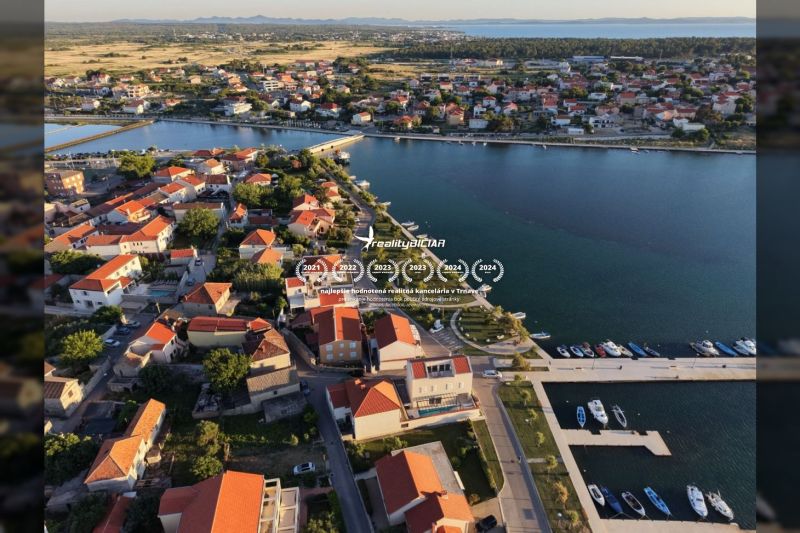 Légi felvétel Nin városának part menti területéről, villák tetejével és kikötővel.