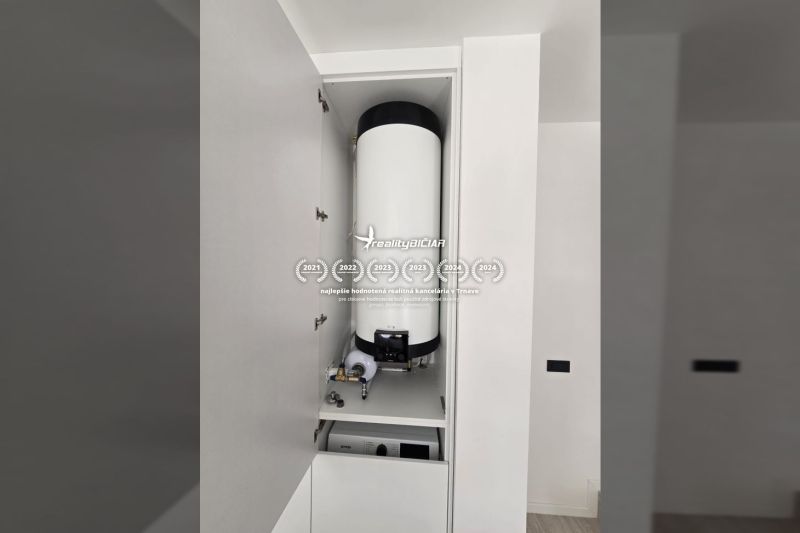 Boiler a szekrényben a villában, fehér fal, egyszerű belső tér.