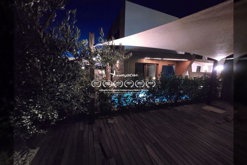 A villa éjszakai kertje Nine-ban medencével és fa dekorációjú padlóval.