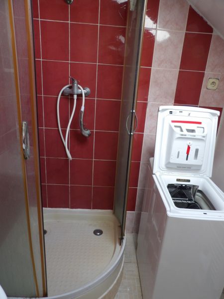 Zuhanykabin a fürdőszobában egy kétszobás lakásban, mosógéppel elhelyezve.