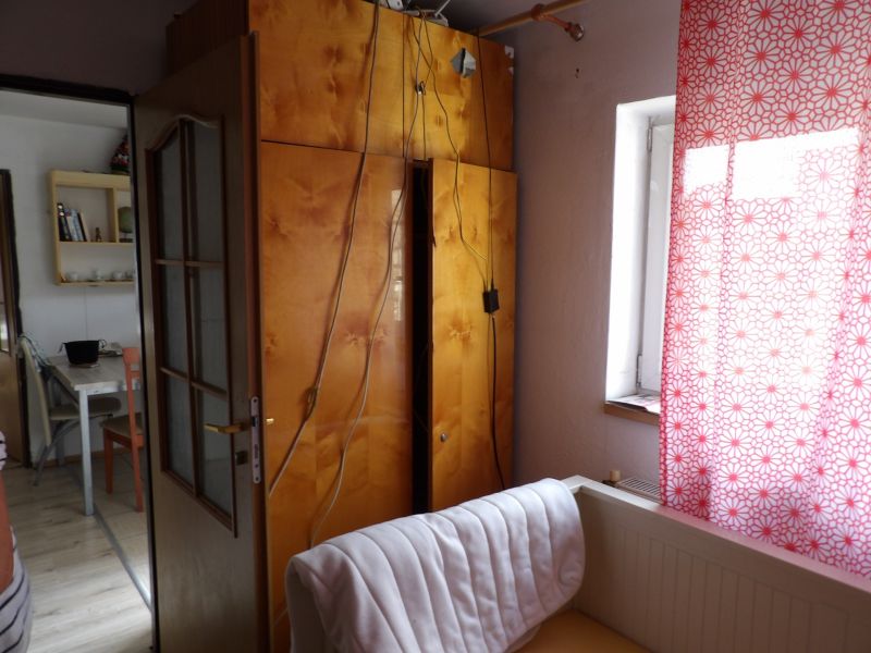 Szoba egy kétszobás lakásban nyitott ajtókkal, szekrénnyel és piros mintás függönnyel.