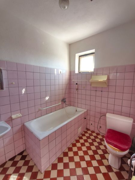 Fürdőszoba rózsaszín csempékkel és fehér káddal egy családi házban.