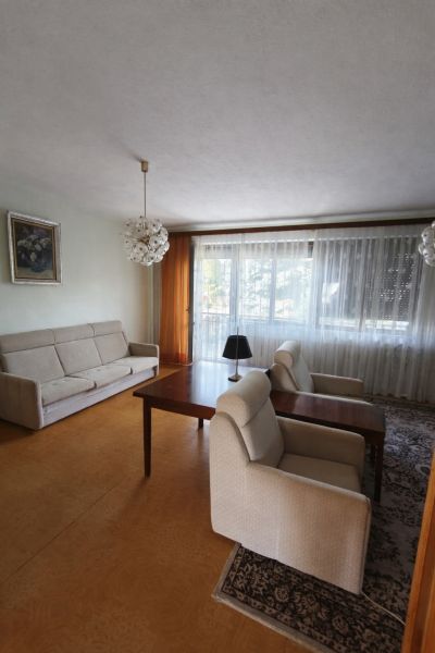Nappali egy családi házban kényelmes ülőhellyel és nagy ablakkal.