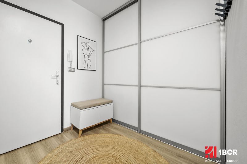 Előszoba egy kétszobás lakásban, fa dekor padlóval és minimalista bútorokkal.