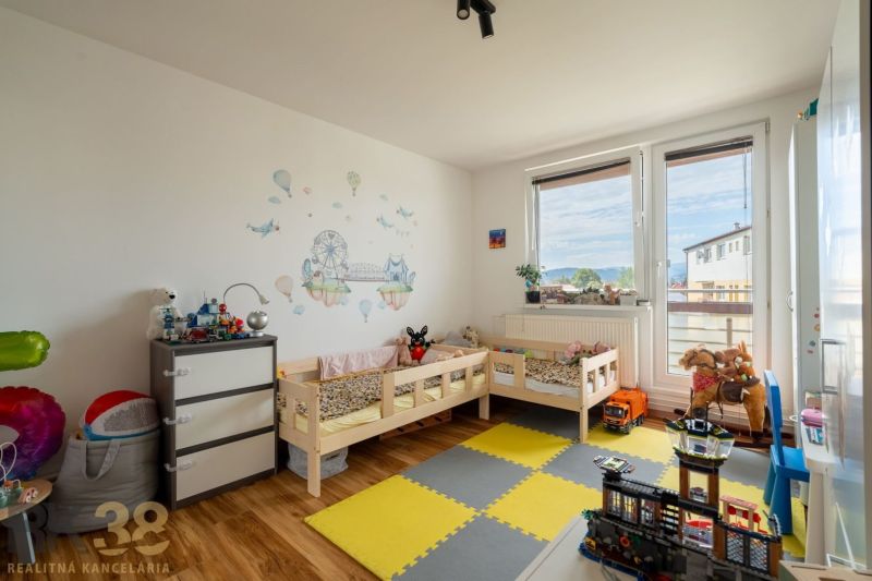 Gyerekszoba két ággyal és matricákkal egy háromszobás lakásban, fa dekoros padlóval.