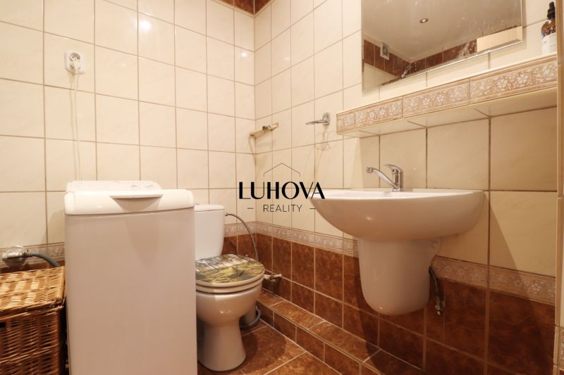 Fürdőszoba egy kétszobás lakásban mosógéppel és WC-vel, finom mintás csempével.
