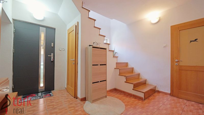 Bejárati folyosó fa dekorációval, lépcsőkkel és tárolóhellyel egy családi házban.