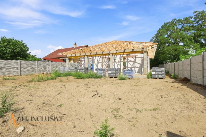 Építés alatt álló családi ház Marcelházán kerítéssel, üres telken fűvel.