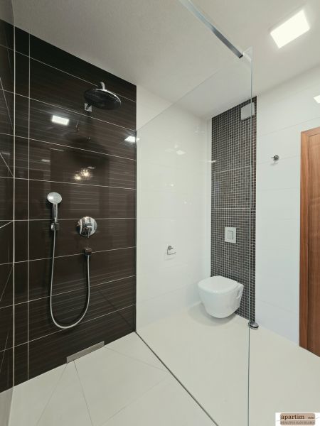 Fürdőszoba zuhanyzóval és függesztett WC-vel egy 4 szobás lakásban.